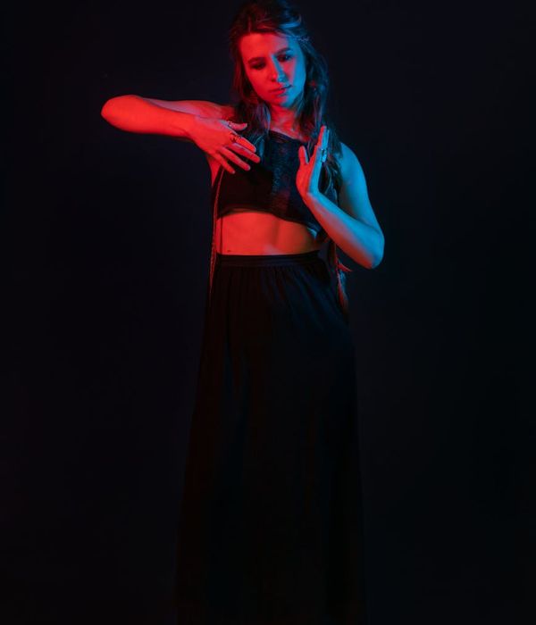 Woman performing a graceful yoga pose in a calm, dark environment.